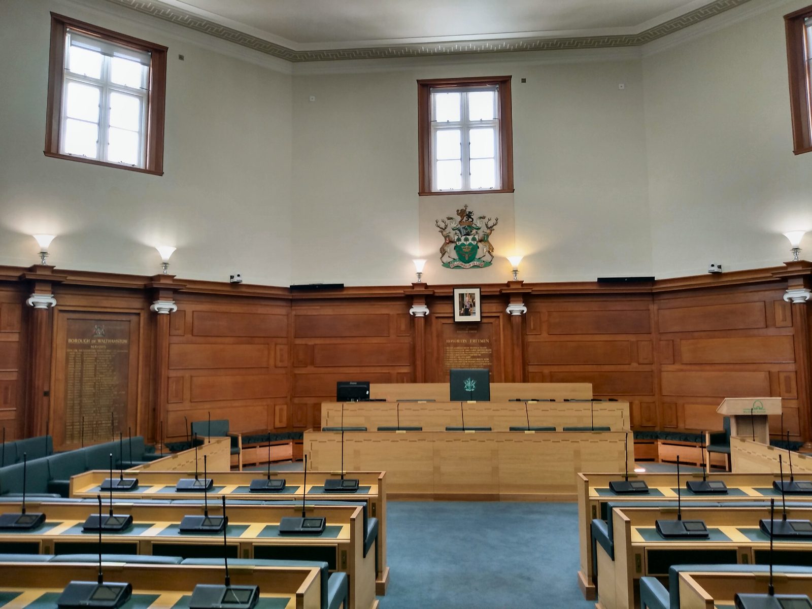 Pusta sala posiedzeń rady miejskiej z rzędami drewnianych ław i mównicą — wnętrze ratusza w Walthamstow.